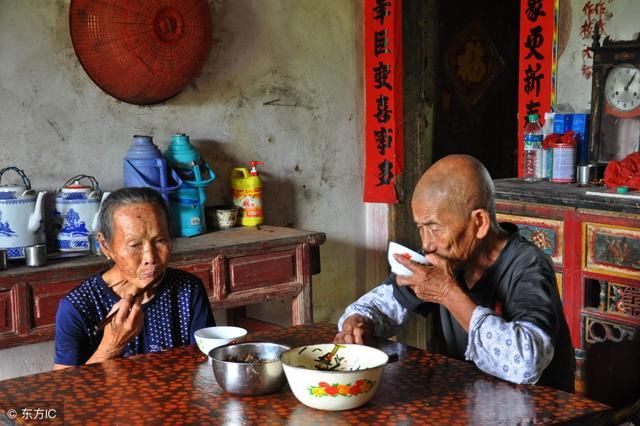 五儿女回老家吃团年饭，饭后他们打牌玩手机，老两口在厨房吃剩菜