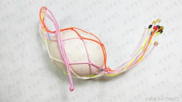 还有3天就是端午节了,在这一天,人们都会送蛋、挂蛋兜,这个习俗已延续两千多年,蕴含着丰富的文化内涵。妈妈将咸蛋煮熟,挂在孩子胸前,祈求孩子有个平安的夏天,孩子们也相互送蛋兜。 今天我就来教大家做蛋兜,做法非常简单 好了,上教程 1、准备6根不同颜色各50cm的线,对折,分别在2厘米处打个蛇结,最好还是用5色,我买的是洋鸡蛋,挺大个的,所以准备了六根 2再如图相邻的两根线两两打蛇结 3、将第一根白色线与最后一根橙色线做一个蛇结,将它连成一个网 4、编第三层蛇结,用同颜色的线编蛇结 5、重复以上编法